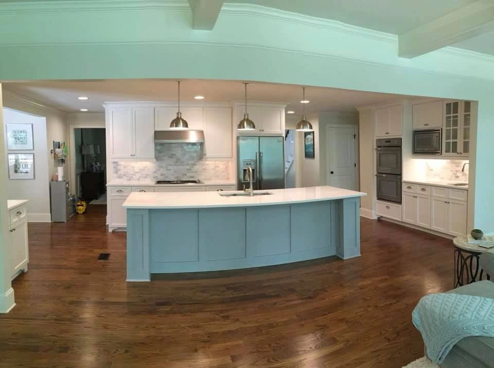 White kitchen with soft green island and hardwood floors