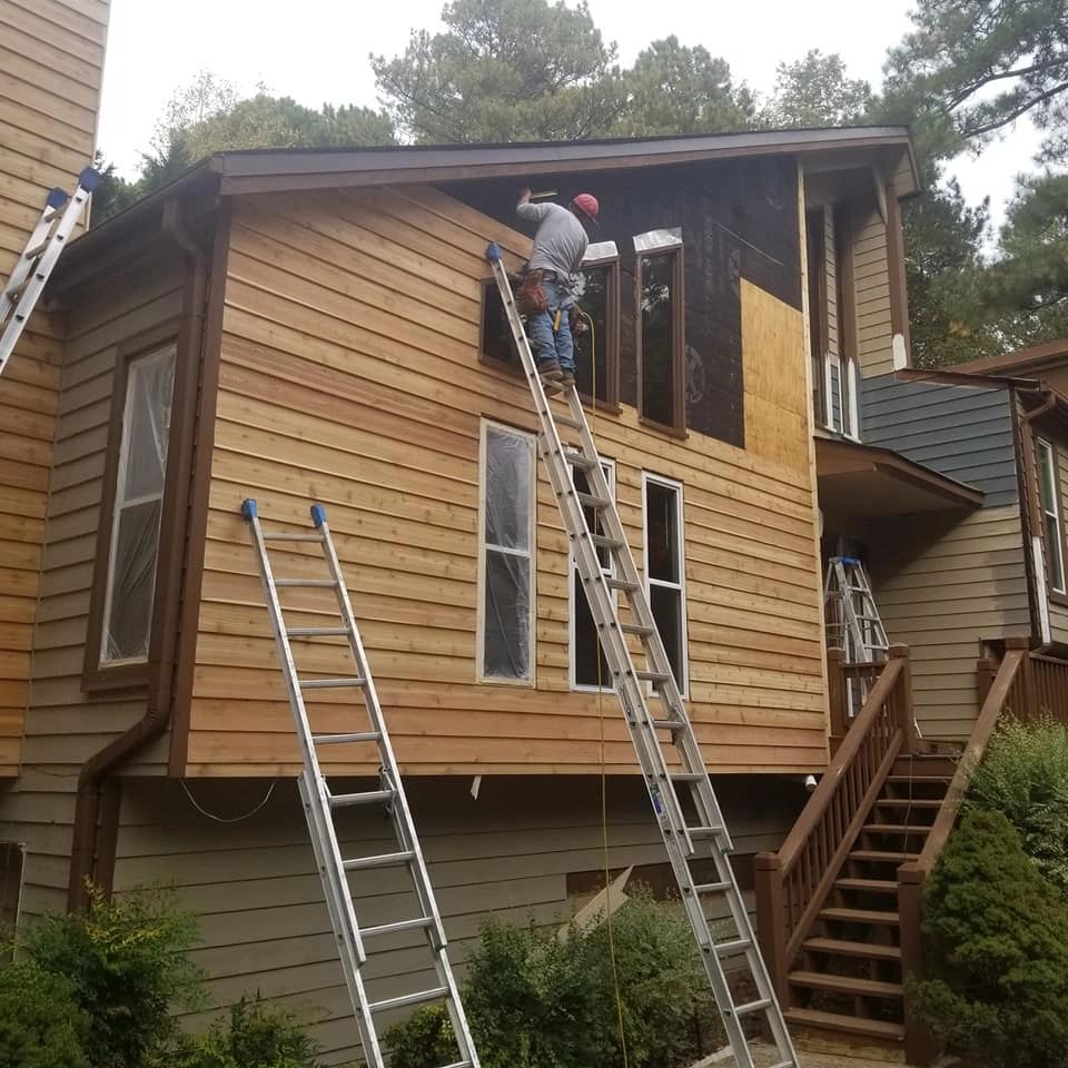 Crew installing new cedar wood lap siding on multi-story home